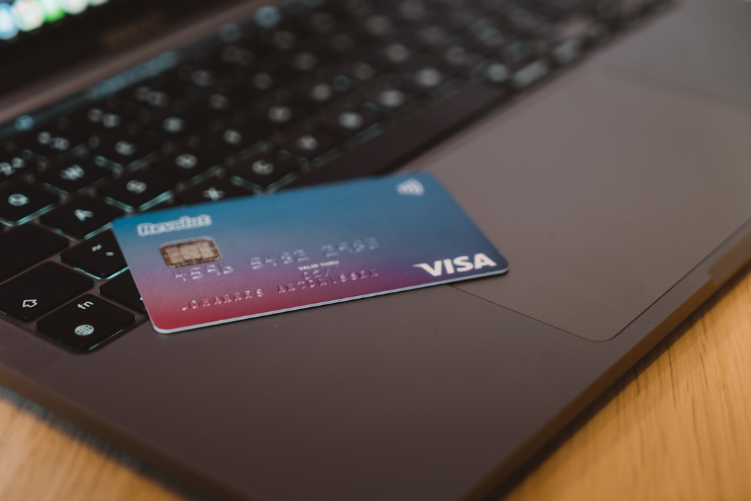 Mano che usa una carta su un POS accanto a un carrello della spesa su laptop, immagine legata ad autenticazione forte, e-commerce e carta rifiutata nei pagamenti online.