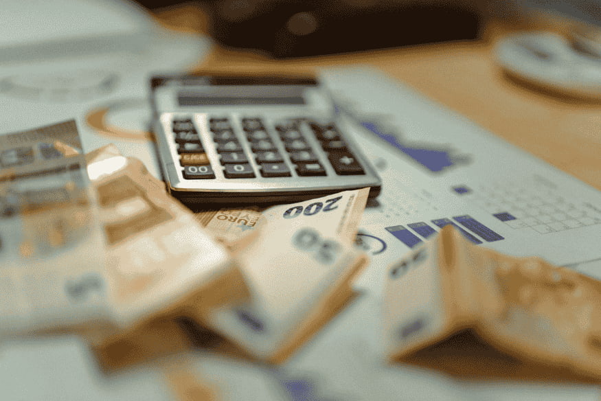Calcolatrice appoggiata su un tavolo con diverse banconote in euro accanto