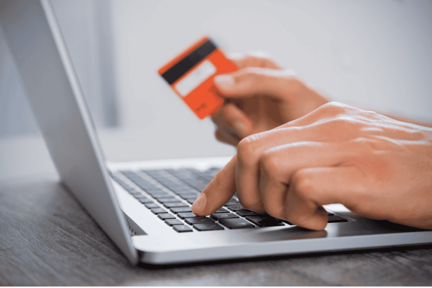 Mano con carta di credito davanti al laptop: acquisti online e pagamento a rate, attenzione a TAN, TAEG e costi extra.
