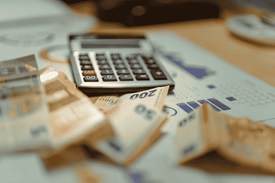 Calcolatrice e banconote su documenti contabili con grafici finanziari.