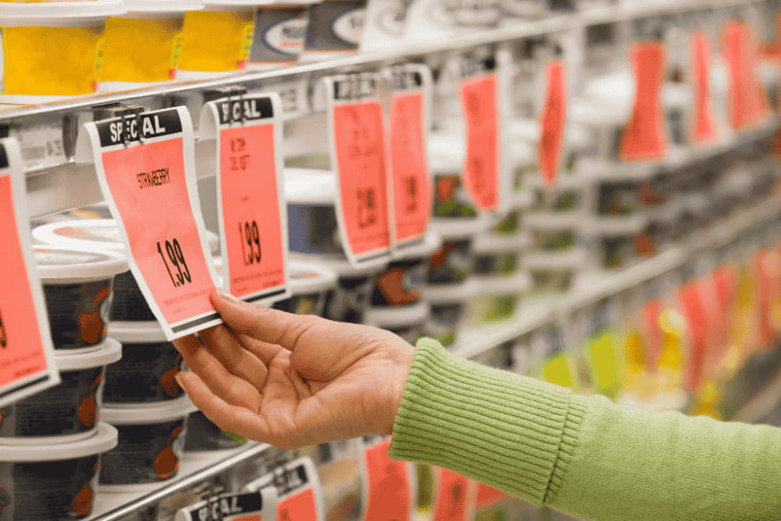 Persona controlla etichette di prezzo in un supermercato.