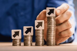 Monete impilate in crescita con frecce verso l’alto che rappresentano aumento dei profitti