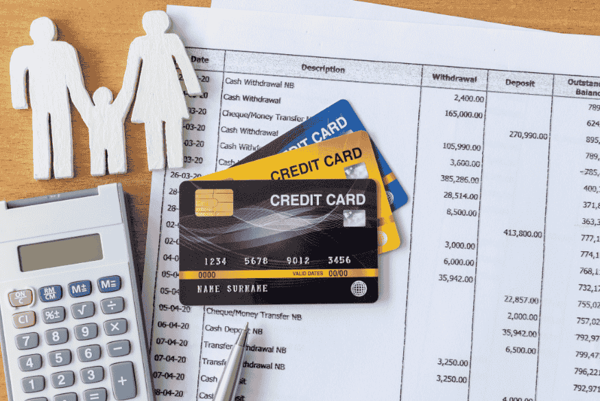 Carte di credito appoggiate su un estratto conto con calcolatrice e sagome familiari, immagine che illustra come leggere l’estratto conto della carta di credito.