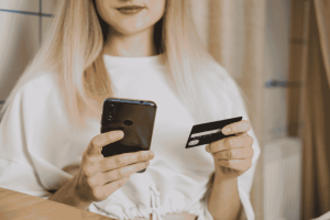 Donna con smartphone e carta di credito: gestione digitale di rate, scadenze e pagamenti per evitare interessi e ritardi.